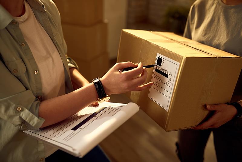 Worker scanning shipping label on cardboard box in warehouse for eCommerce order fulfillment