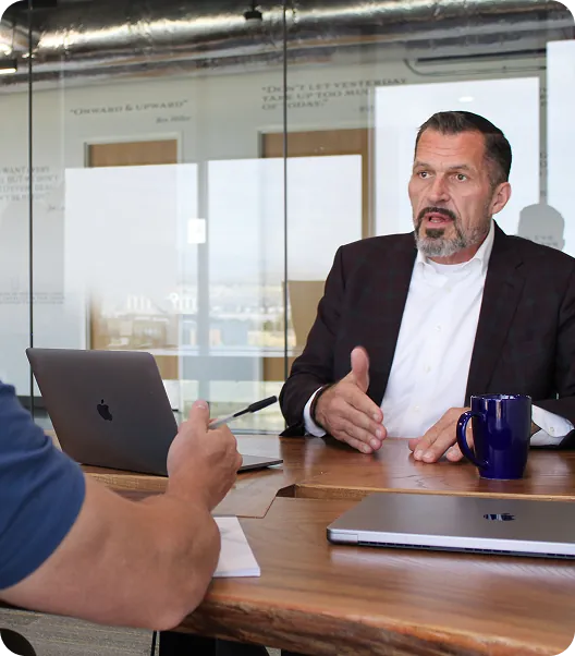 Businessman discussing logistics solutions in office setting with laptop and documents