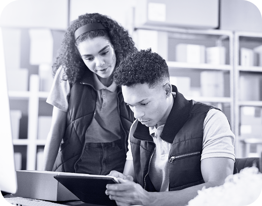 A photo of two people looking over a box and tablet